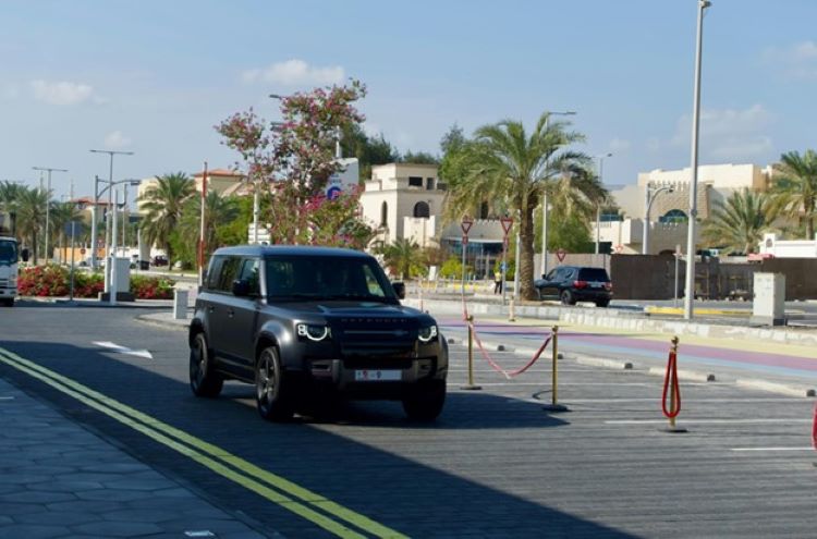 A black SUV driving down a street next to palm trees in Abu Dhabi